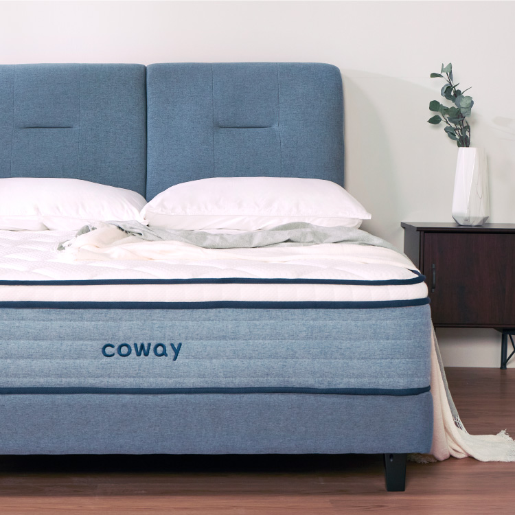 front-view-of-coway-prime-lite-series-mattress-with-complete-bedsheets-and-a-blue-bedframe-along-a-side-table-with-a-plant